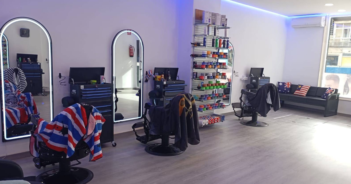 Interior de Ibra & Nor con varios sillones de barbero, espejos arqueados y estantes de productos.