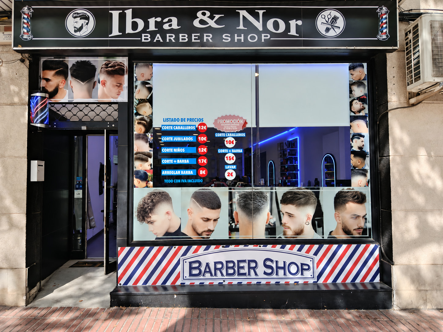 Fachada de Ibra & Nor Barber Shop en la calle Alcalá, con el rótulo negro, el escaparate y la cenefa roja, blanca y azul.